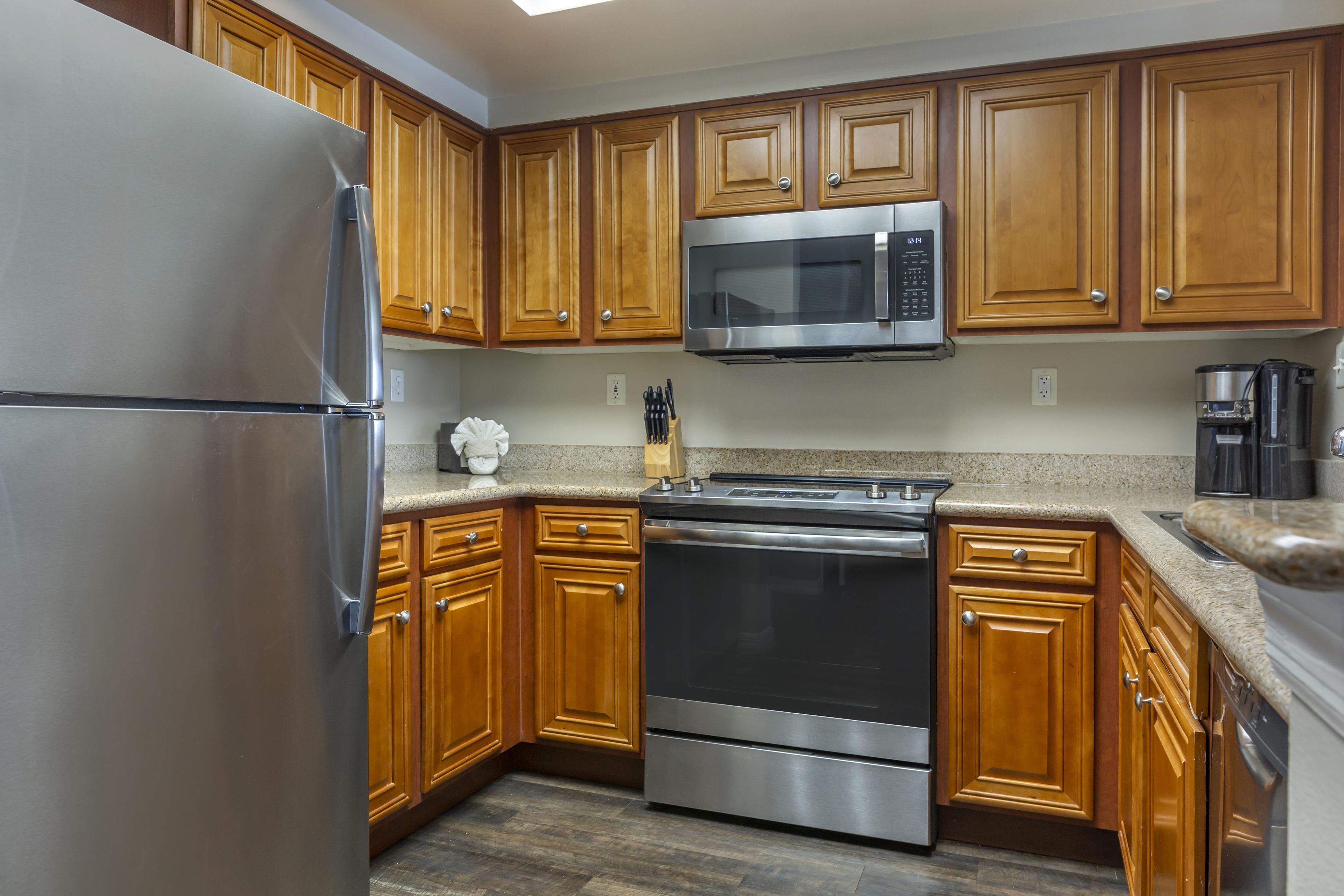 A modern kitchen with wooden cabinets, stainless steel appliances, and granite countertops.