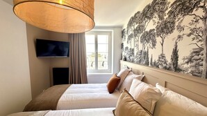 Een hotelkamer met een groot bed, een televisie aan de muur en een raam met gordijnen.