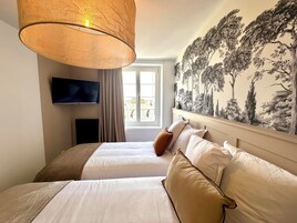 Une chambre d’hôtel avec un grand lit, un téléviseur fixé au mur et une fenêtre avec des rideaux.