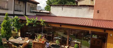Un patio con mobiliario exterior, una mesa de madera y plantas en macetas.
