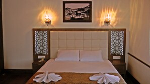 Una habitación de hotel con una cama grande, dos lámparas fijadas a la pared y un cuadro enmarcado sobre la cama.