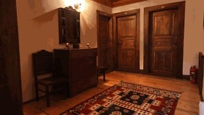 Una habitación con piso de madera, un tapete estampado, un escritorio de madera con una silla y dos puertas de madera.