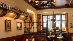 Un espace de restauration traditionnel avec des tables et des chaises en bois, un lustre et une fenêtre agrémentée de rideaux.