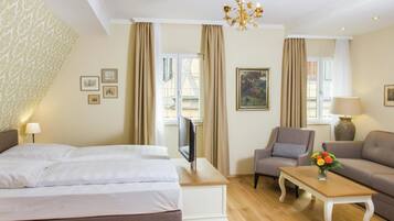 A hotel room with a bed, a television, a sofa, a chair, and a small table.