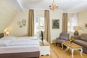 Ein Hotelzimmer mit einem Bett, einem Fernseher, einer Couch, einem Sessel und einem kleinen Tisch.