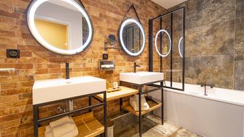 Une salle de bain moderne avec deux lavabos, un grand miroir et une baignoire.