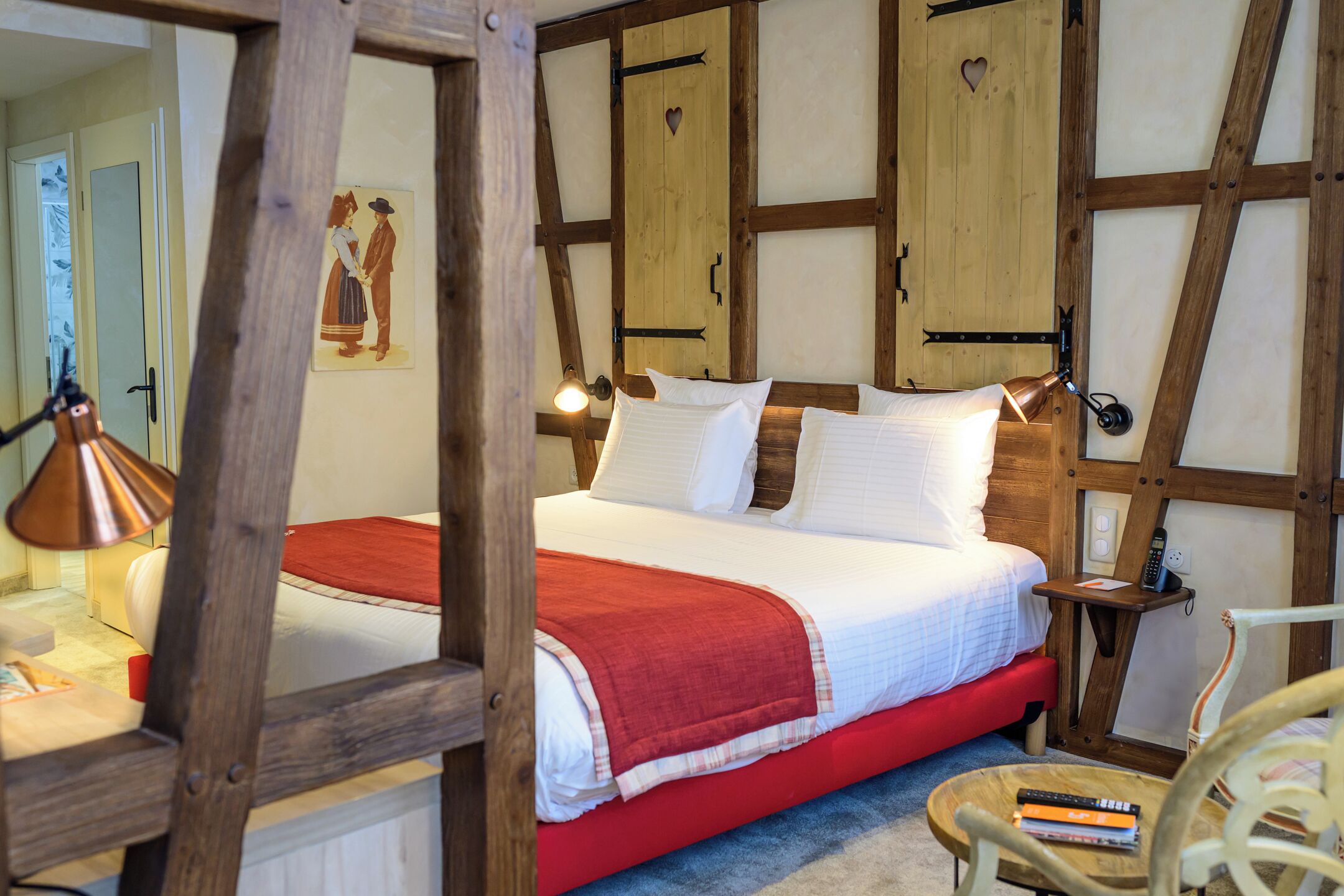 Ein traditionell eingerichtetes Zimmer mit einem hölzernen Bett, einer roten Bettdecke und einem kleinen Nachttisch mit einer Lampe.
