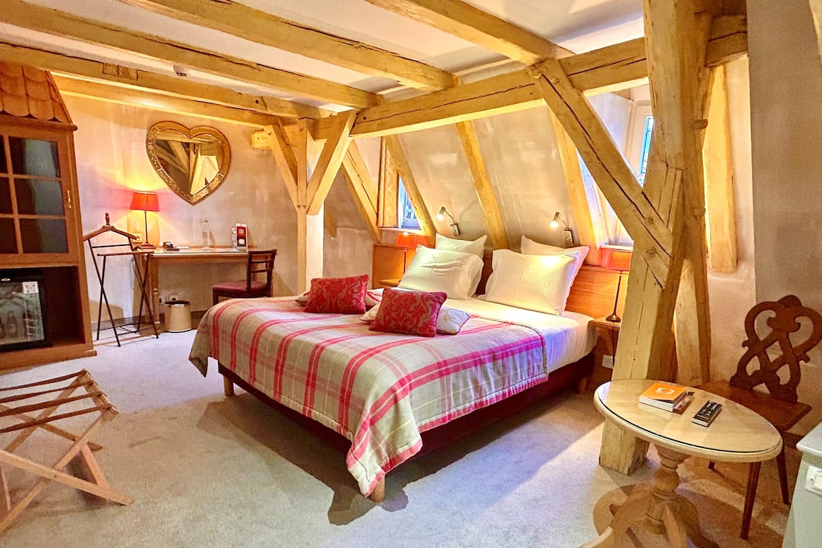 A cozy bedroom with a bed, bedside table, and a desk with a chair.