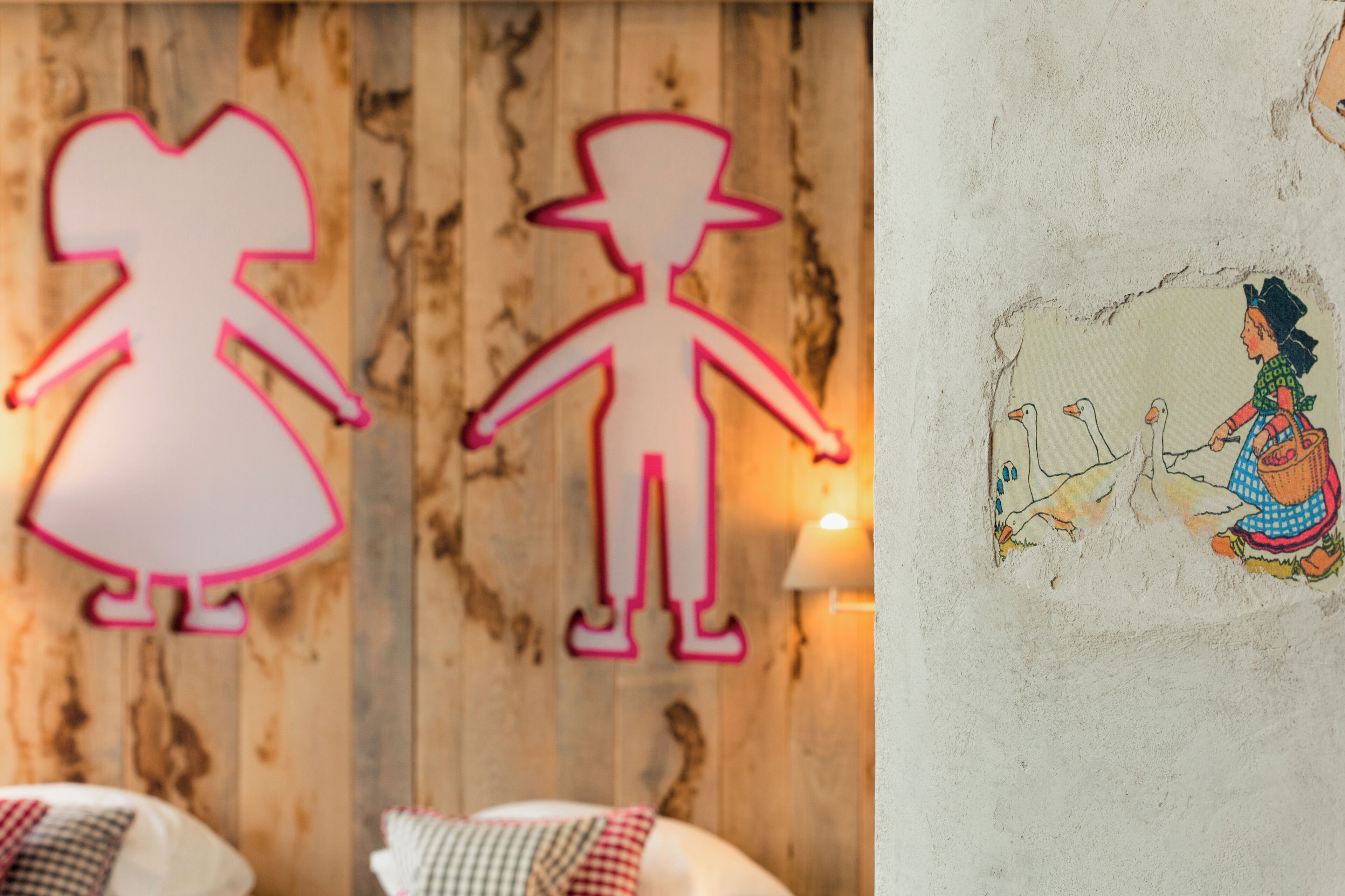 A room with a wooden wall and a mural of a woman with geese.