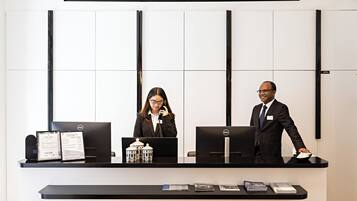 A reception desk with two computer monitors, a framed menu, and brochures.