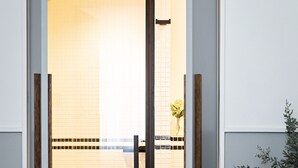 A bedroom with a bed, a striped blanket, a wooden door, and a view of a tiled wall and a plant. - Best Western Premier The Blake Paris Gare Saint Lazare (Paris)