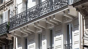 A building with ornate black wrought iron balconies, a sign for 'Premier Best Western The Blaise Paris Saint-Lazare', and awnings over the entrance.