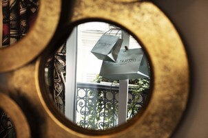 Una vista attraverso una finestra circolare con una borsa della spesa appesa a una ringhiera.