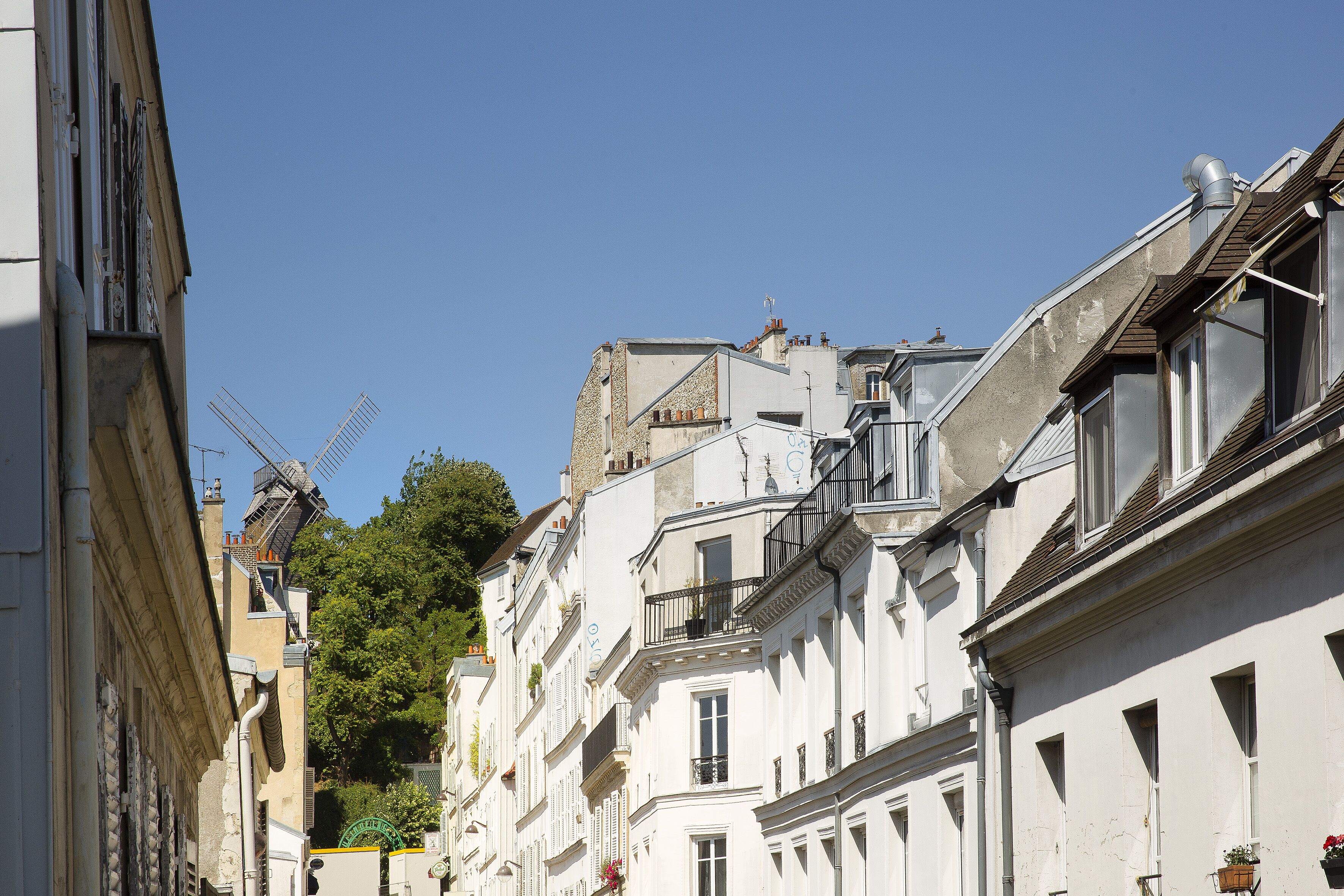 Une rangée de bâtiments historiques blancs, dotés de balcons, avec un moulin à vent en arrière-plan.