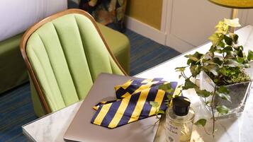 A laptop on a marble table with a striped cloth, a bottle of eau de cologne, and a potted plant.