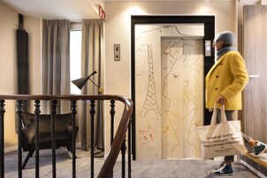 A hotel lobby with a staircase, a black chair, and a door with a cat drawing.
