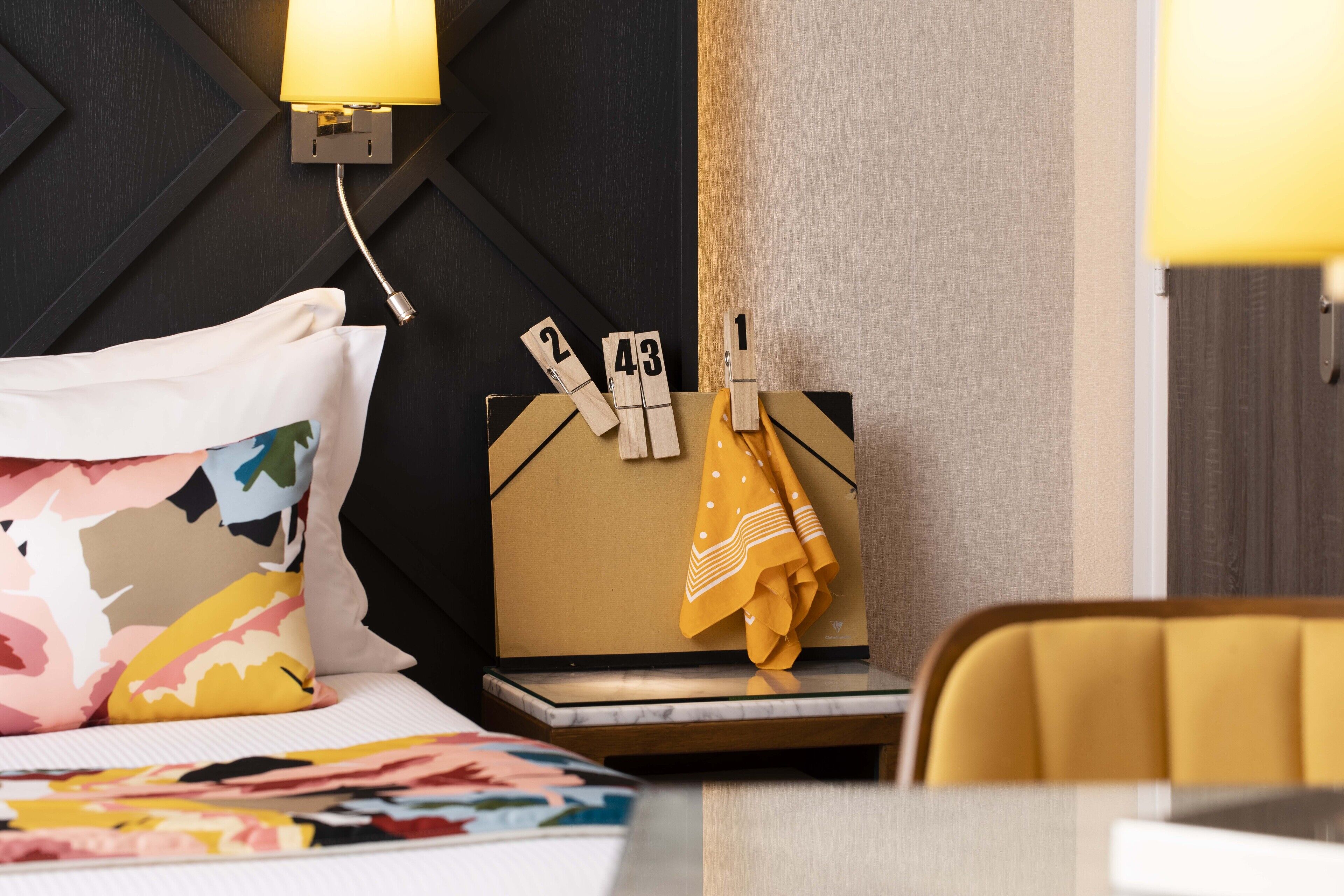 Una habitación de hotel con una cama, una mesita de noche, una lámpara y un reloj en la pared.