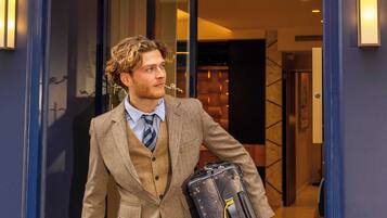 A man in a suit exiting a hotel with a briefcase.