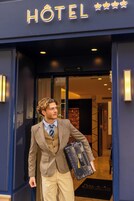A man in a suit exiting a hotel with a briefcase.