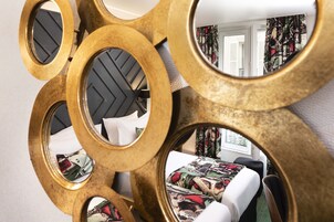 A bed with a floral bedspread, a black headboard, and a mirror with a gold frame.