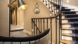 A spiral staircase with wooden steps and black balusters, a wall-mounted mirror, and a pendant light with a textured shade. - Hotel Des Arts Paris Montmartre (Paris)