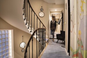 A staircase with a curved design, a mirror, and a wall with a mural.