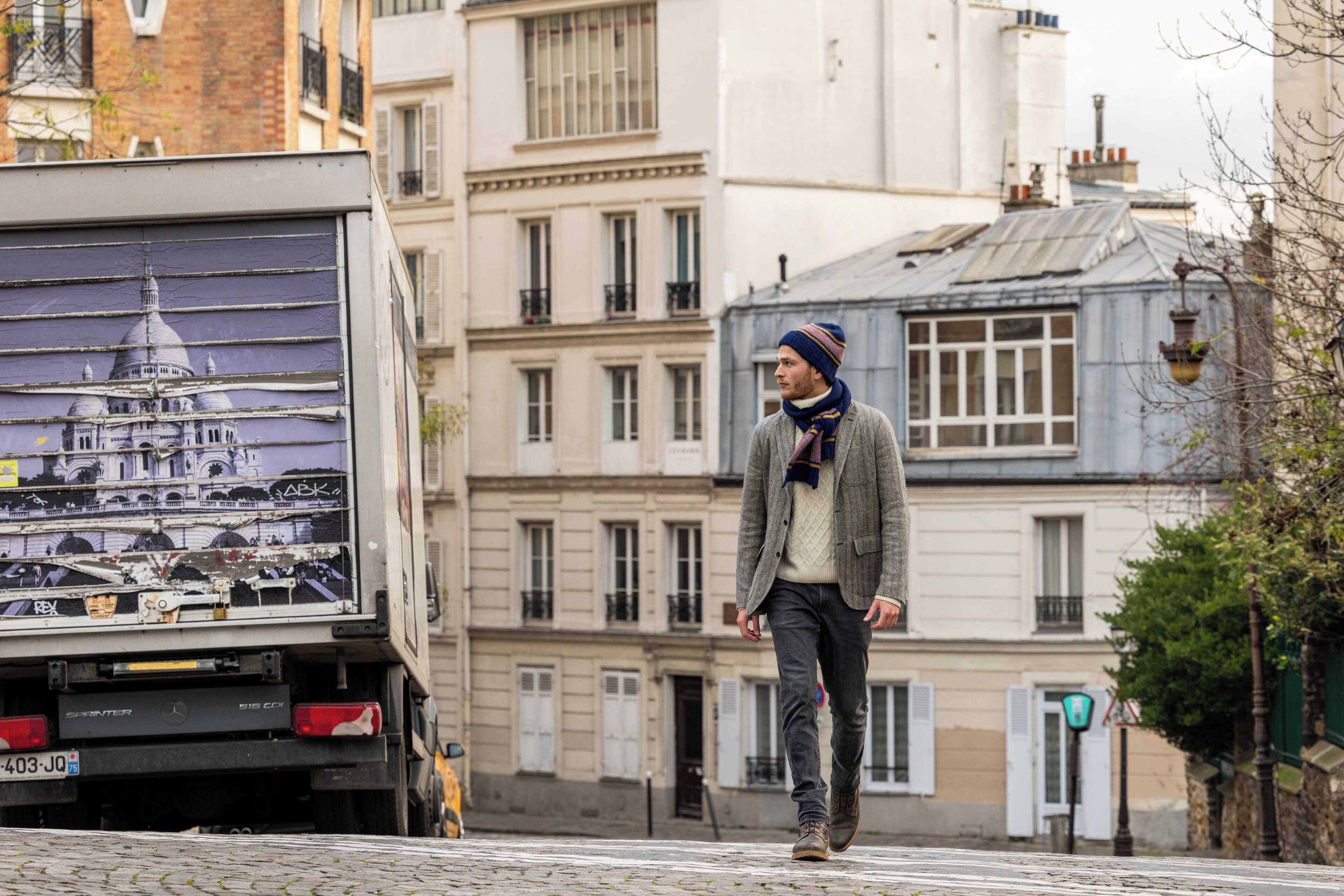 A man walking past a truck with a large image of a building on its back.