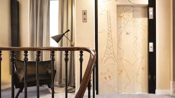 Un vestíbulo de hotel con una escalera, un sofá y una puerta con diseños artísticos.