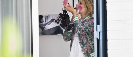 A person standing by a window, holding a pink object.