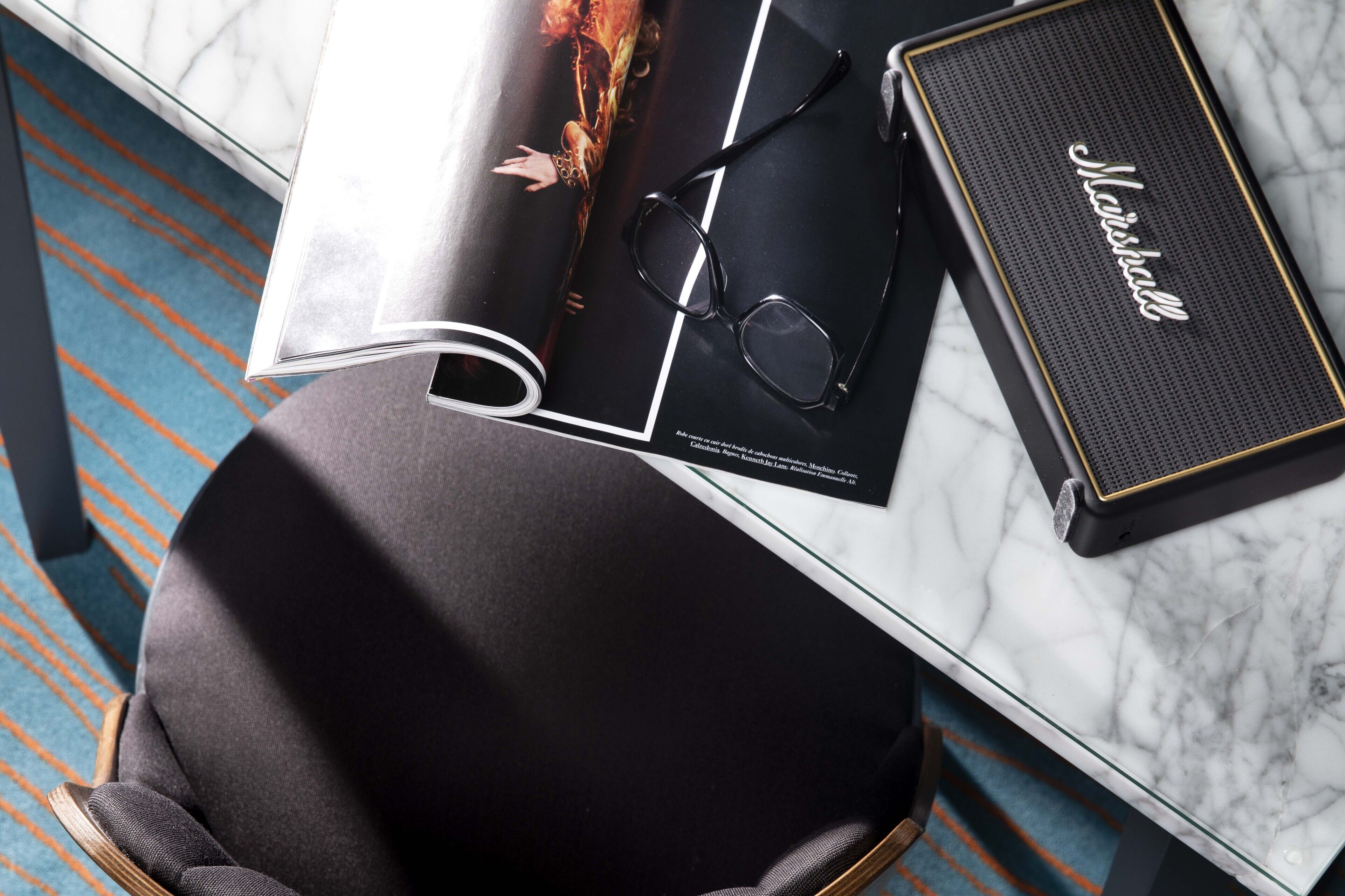 Uma revista, um par de óculos e um amplificador Marshall sobre uma mesa de mármore.