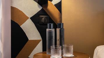 A small round table with two glasses and two bottles, a wall with a geometric pattern, and a hanging light fixture.