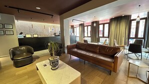 Una hall moderna con un divano in pelle, una reception e una pianta in vaso.