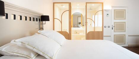 A hotel room with a large bed, a bedside lamp, a mirror, and a wardrobe with a mirror.