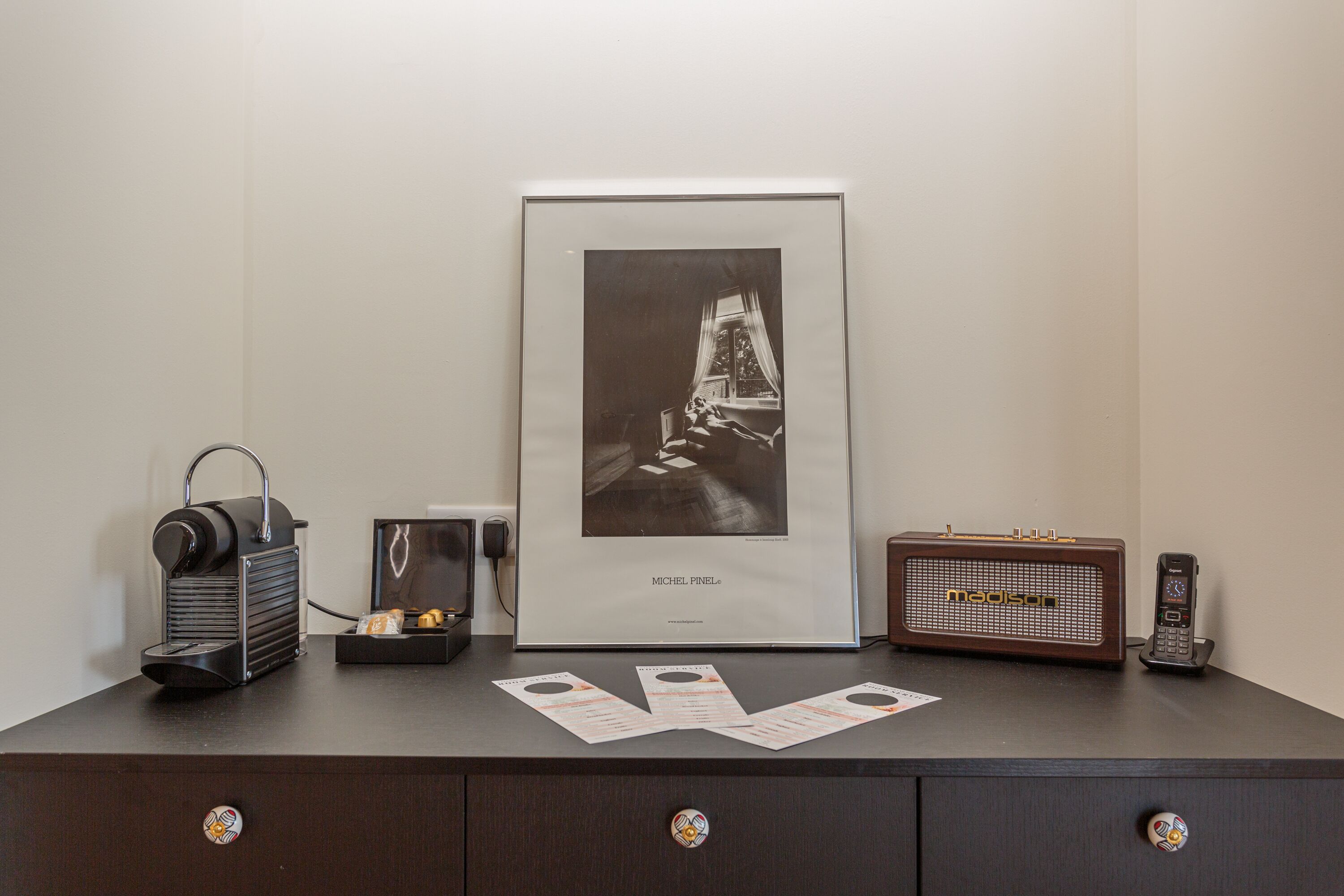 A desk with a vintage radio, a framed photograph, and a coffee maker.