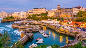 A coastal cityscape with historic buildings, a harbor with boats, and a prominent church. - Grand Tonic Hotel & SPA NUXE (Biarritz)