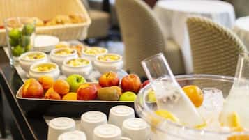 A buffet setup with various fruits, bowls of food, and white cups on a table in a hotel dining area.
