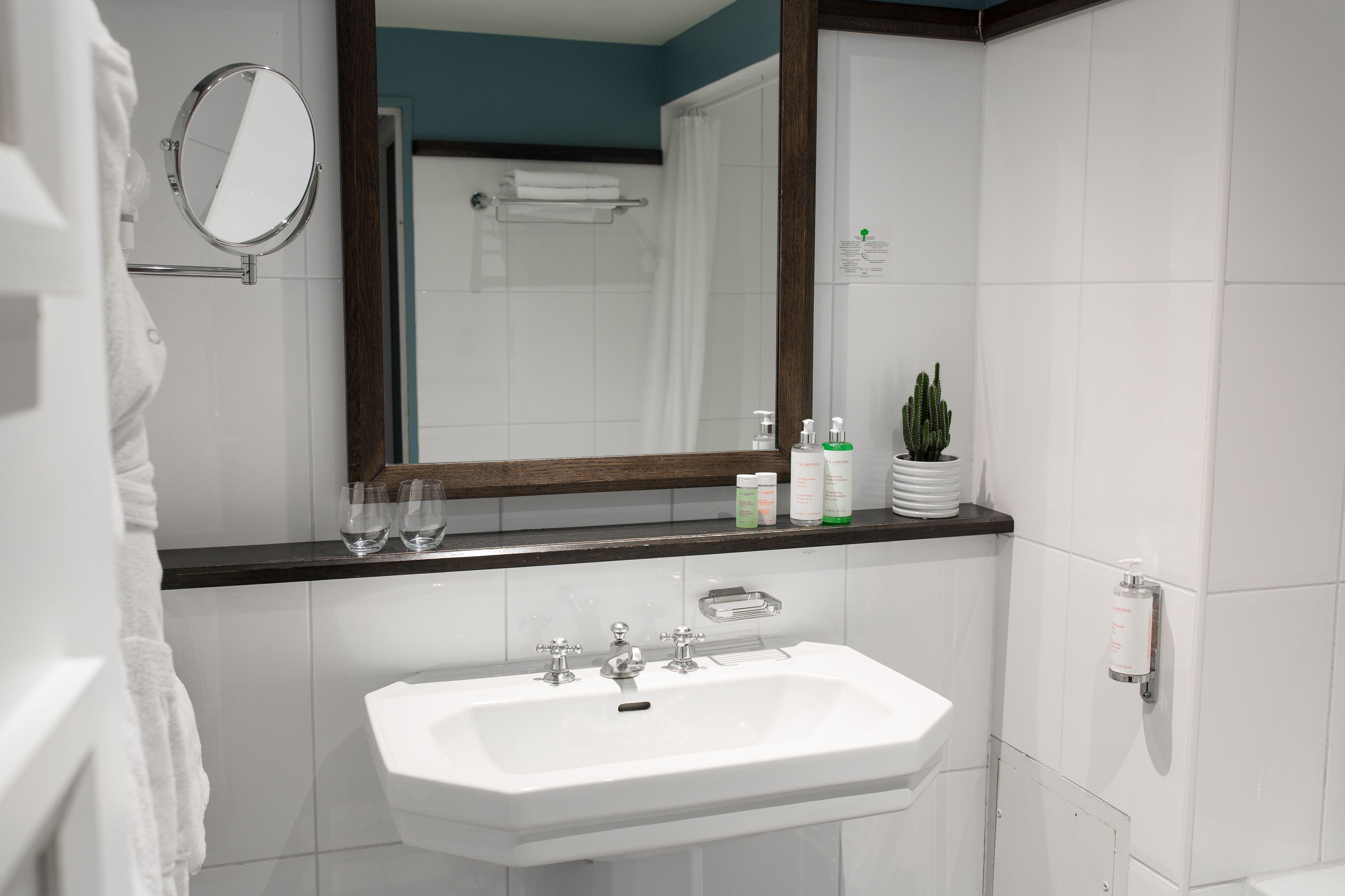 A bathroom with a white sink, a mirror, and a shower area.