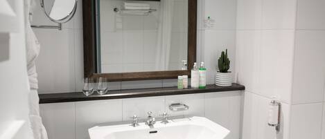 A bathroom with a white sink, a mirror, and a shower area.