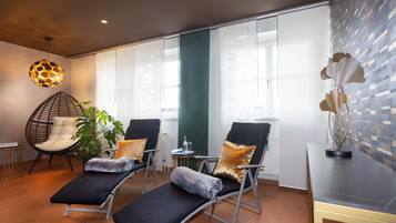 Una habitación con dos sillones reclinables, una lámpara colgante, una planta y un adorno en la pared.