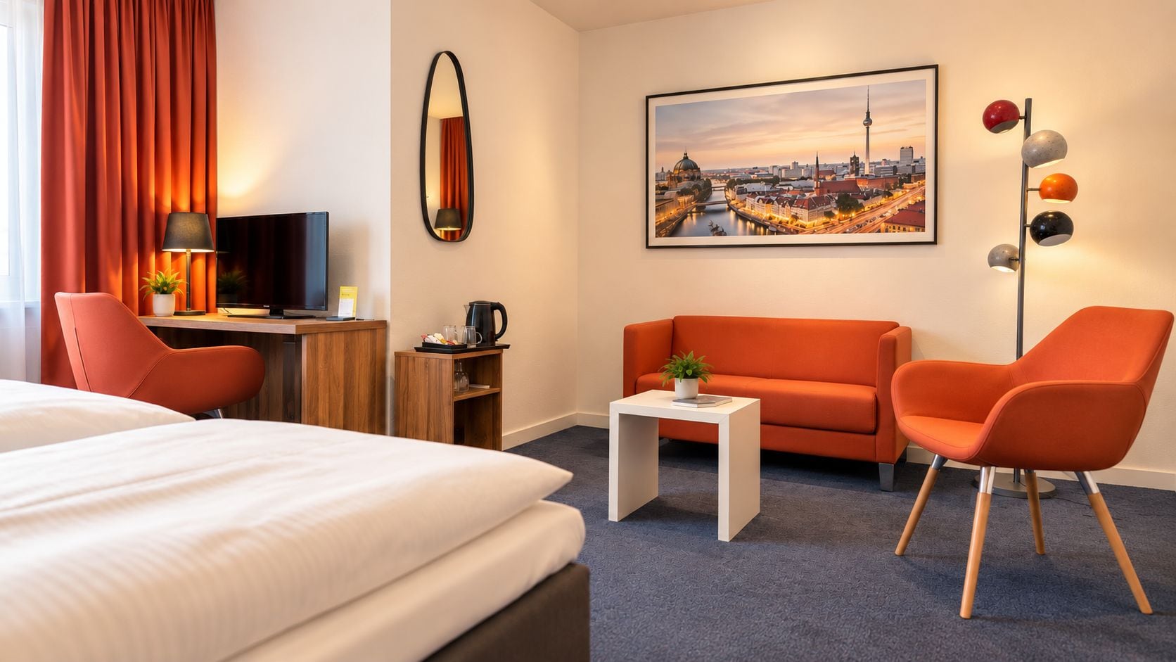 Quarto de hotel com cama, escrivaninha, sofá e mesa de centro.