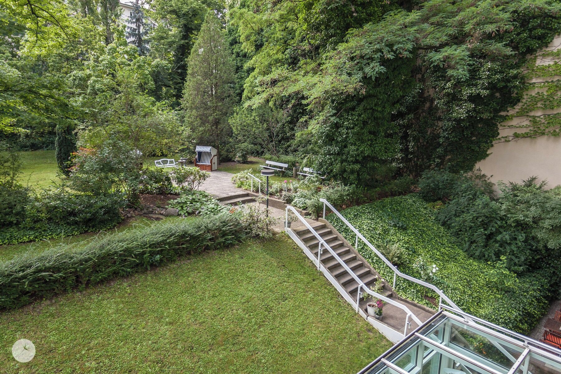 A garden with a staircase leading to a seating area surrounded by lush greenery.
