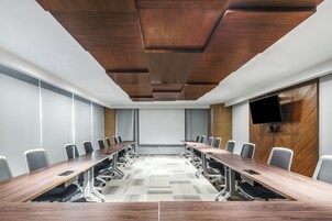 Una sala de conferencias con una mesa larga, sillas y una pantalla para proyector.