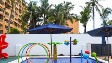 Relax by the pool surrounded by palm trees and lounge chairs, featuring water play features and a refreshing atmosphere.