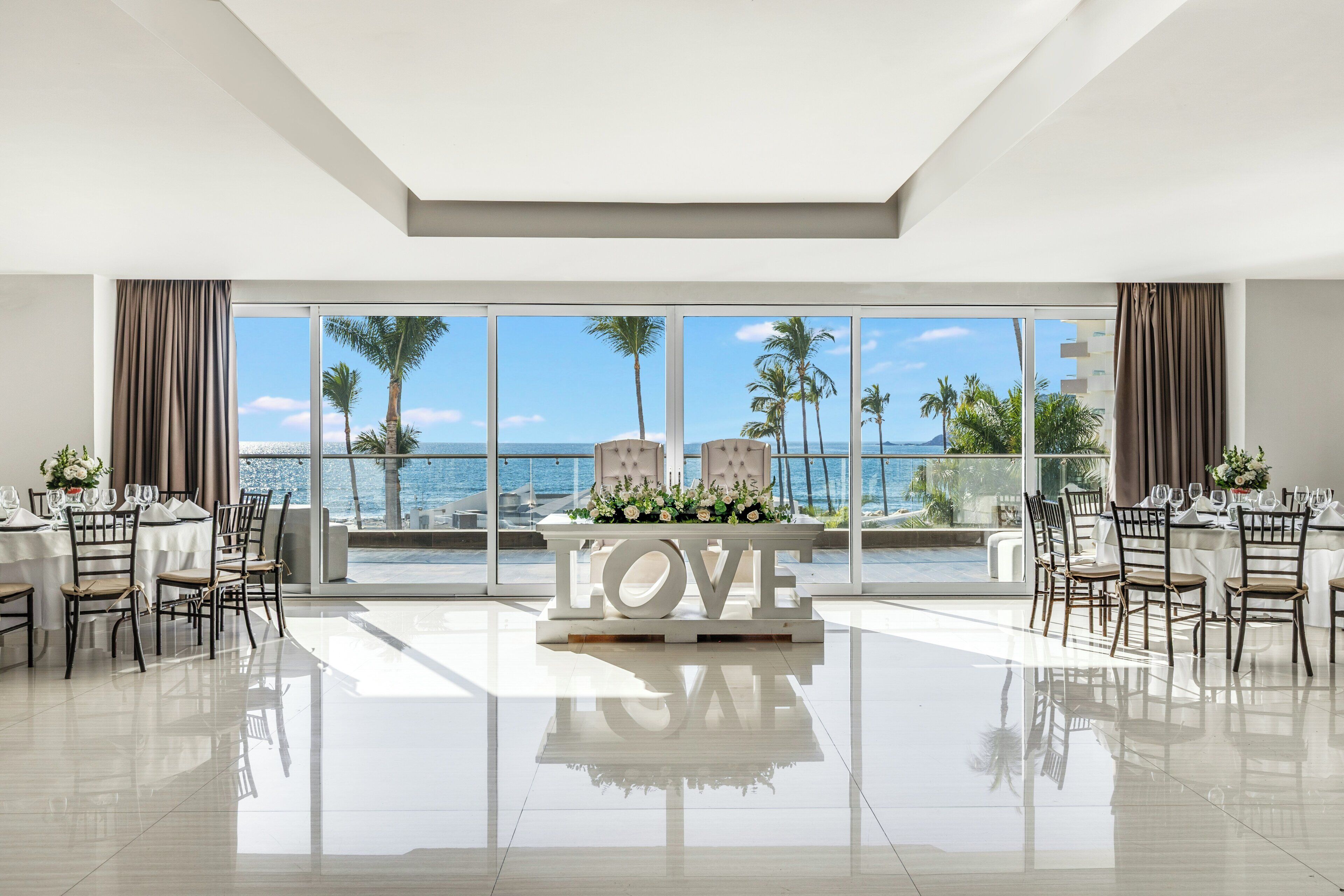 A spacious dining area with a view of the sea, a 'LOVE' centerpiece, and a modern interior design.