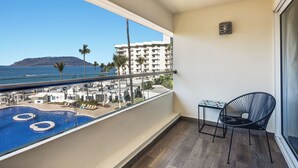 A balcony with a view of a swimming pool, a chair, and a table.