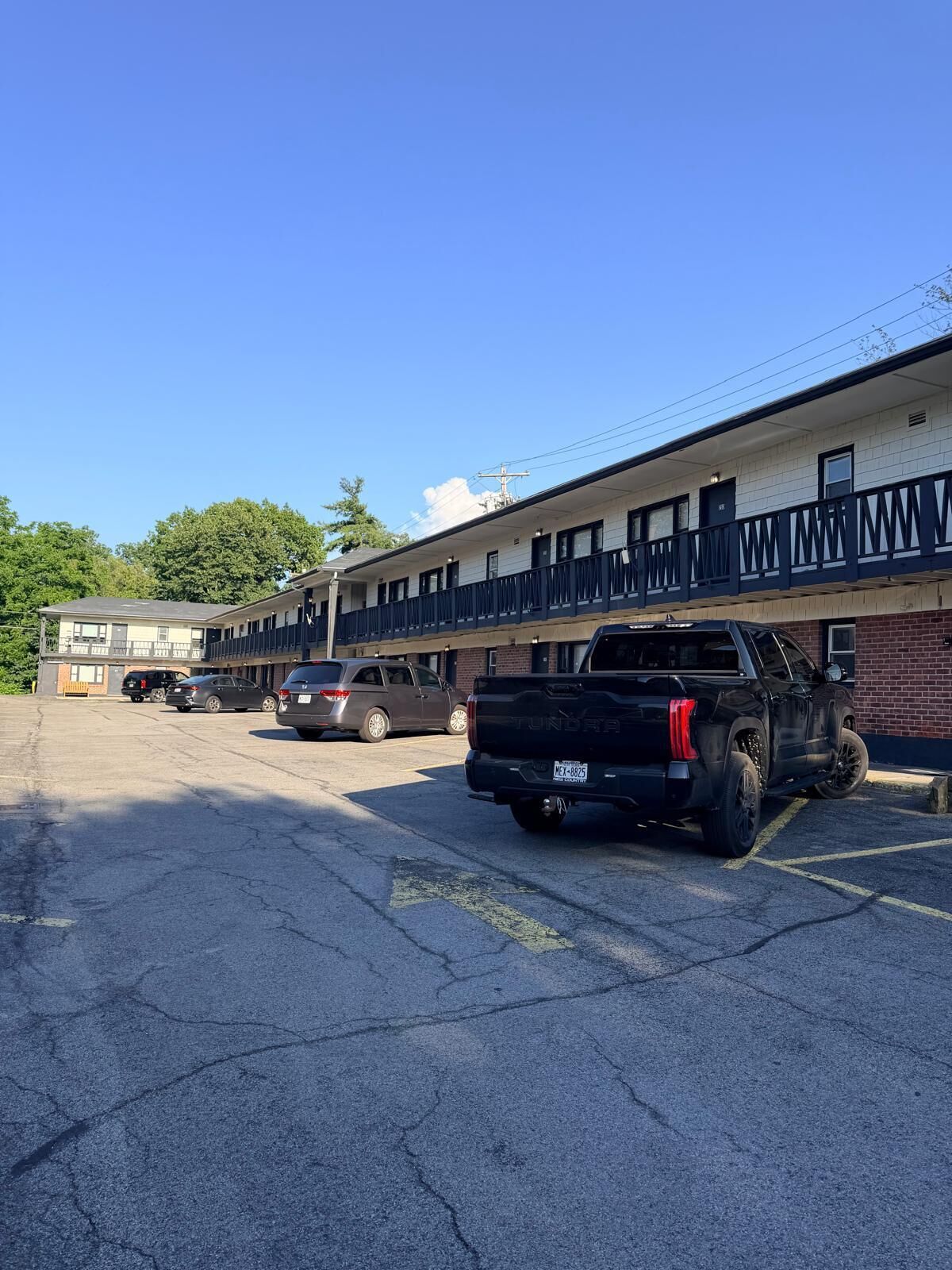 A motel with a parking lot, a black truck, and a building with a balcony.
