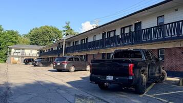 A motel with a parking lot, a black truck, and a building with a balcony.