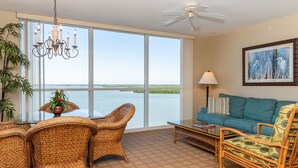 A spacious living area with wicker furniture, a view of the water, a ceiling fan, and a framed artwork on the wall. - Lovers Key Resort (Fort Myers Beach)