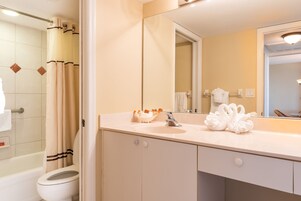 A bathroom with a bathtub, toilet, sink, and a large mirror.