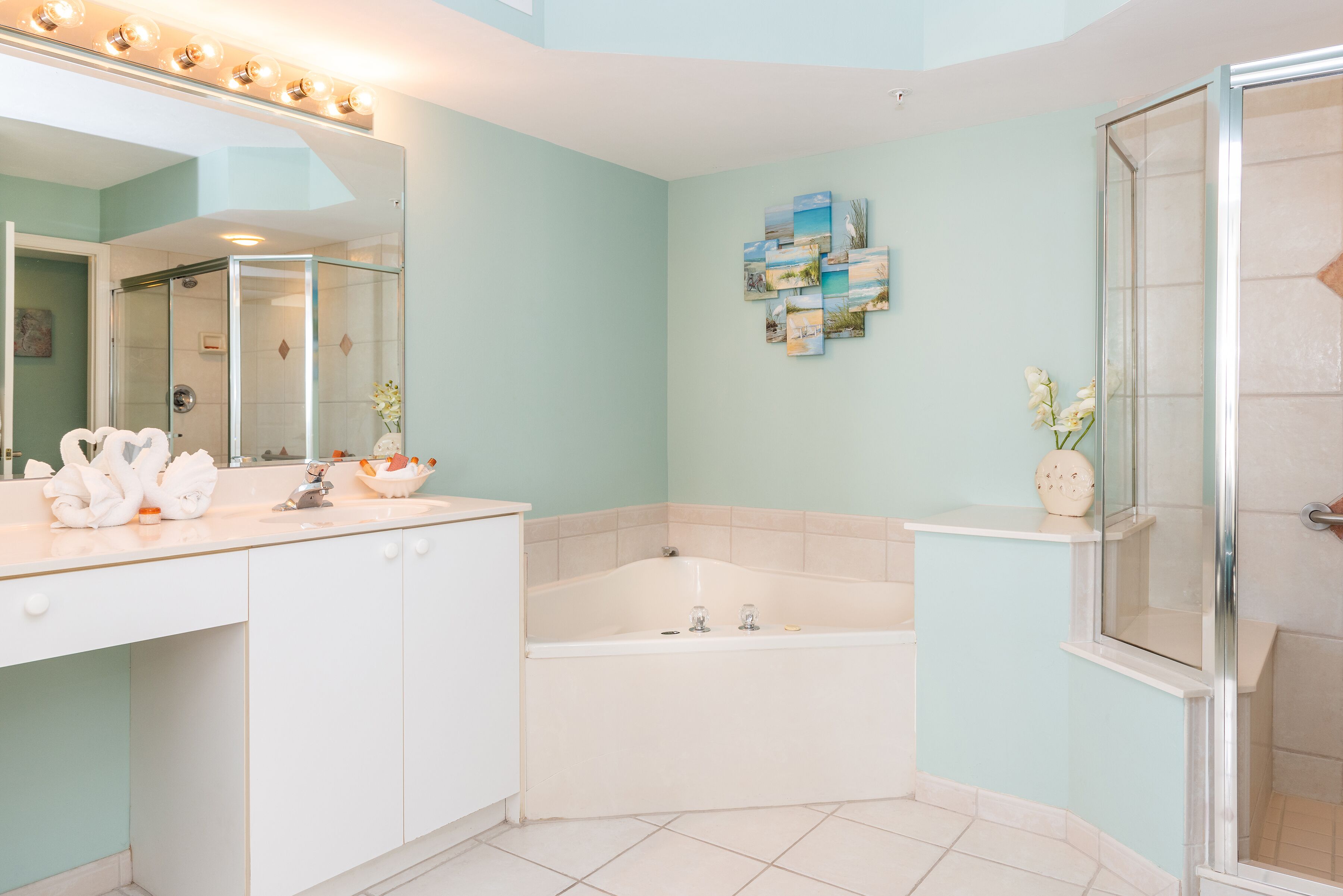 A bathroom with a large mirror, a bathtub, a shower, and a sink with toiletries.